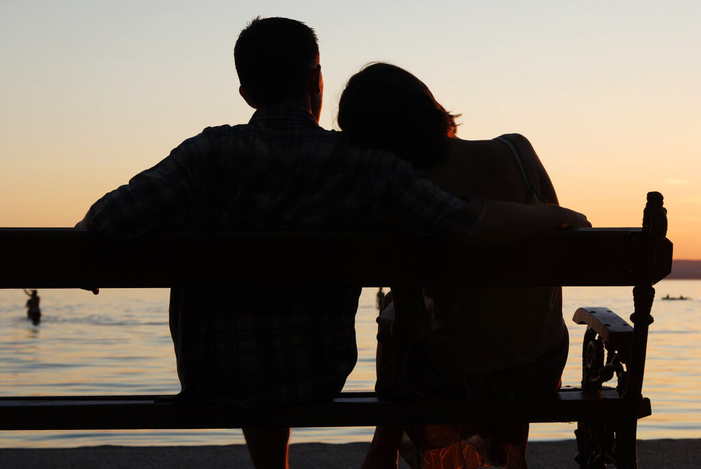 Picture of a couple sitting together on a bench at sunset. Are you seeking peace in your relationship? Working with a relationship therapist in Delray Beach, FL, can  help you achieve open communication. 