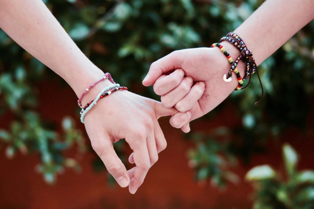 Photo of friends holding hands and wearing friendship bracelets. Setting boundaries can actually promote healthier relationships. Learn how to set and stick to boundaries through relationship therapy in Delray Beach, FL. 