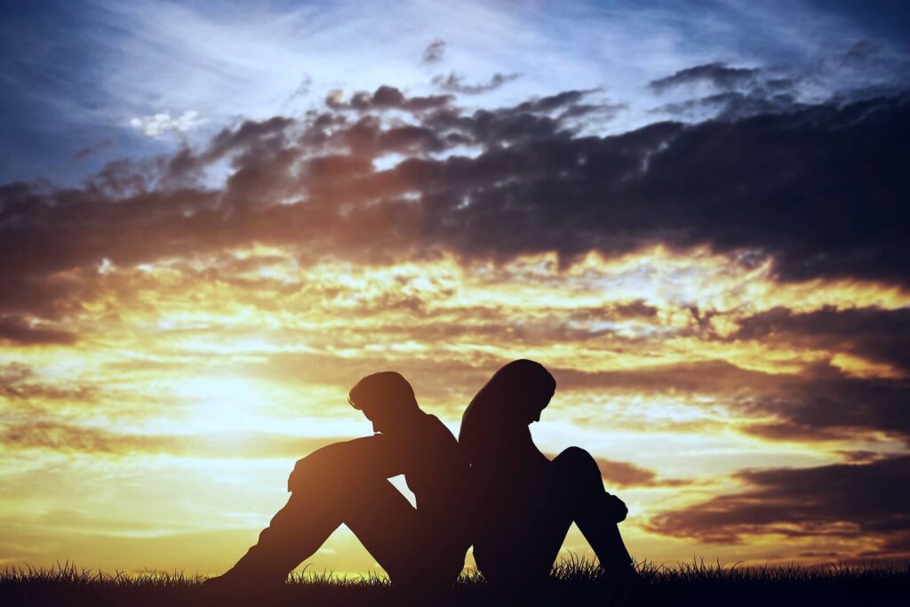Silhouette of a sad couple sitting back to back. If your partner partakes in morally destructive behavior, a relationship therapist in Delray Beach, FL, can help you heal from gaslighting and make sense of it all.