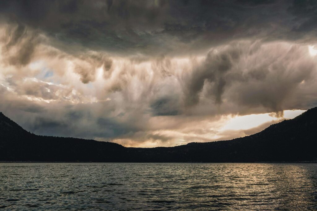 Dark clouds gather above calm waters with mountains in the distance. Relationship anxiety can feel heavy, like a storm over your connection. Relationship therapy in Delray Beach, FL, can help ease tension and strengthen trust between partners.