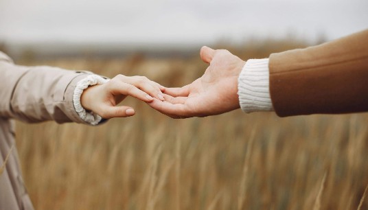 Two hands gently reach for each other in a wheat field, symbolizing trust and reconnection. Marriage expectations can shift over time and cause strain. Relationship therapy in Delray Beach, FL supports couples in redefining their future together.