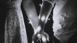A couple holds hands in soft light with string lights wrapped around their wrists. Power in a relationship can be both connection and control. A relationship therapist in Delray Beach, FL, helps partners rediscover healthy emotional balance and connection.