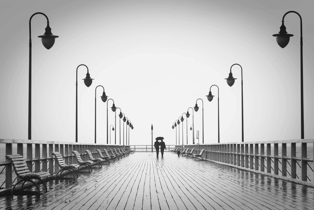 Rainy boardwalk | happy marriage delray beach | relationship counseling | relationship fading love | Highland Beach | Juno Beach | Loxahatchee A couple walking closely together under an umbrella on a rainy boardwalk. Do you long for the warmth of a happy marriage but feel your connection slipping away? A relationship therapist in Delray Beach, FL, can help you rediscover love and connection through healing conversations.