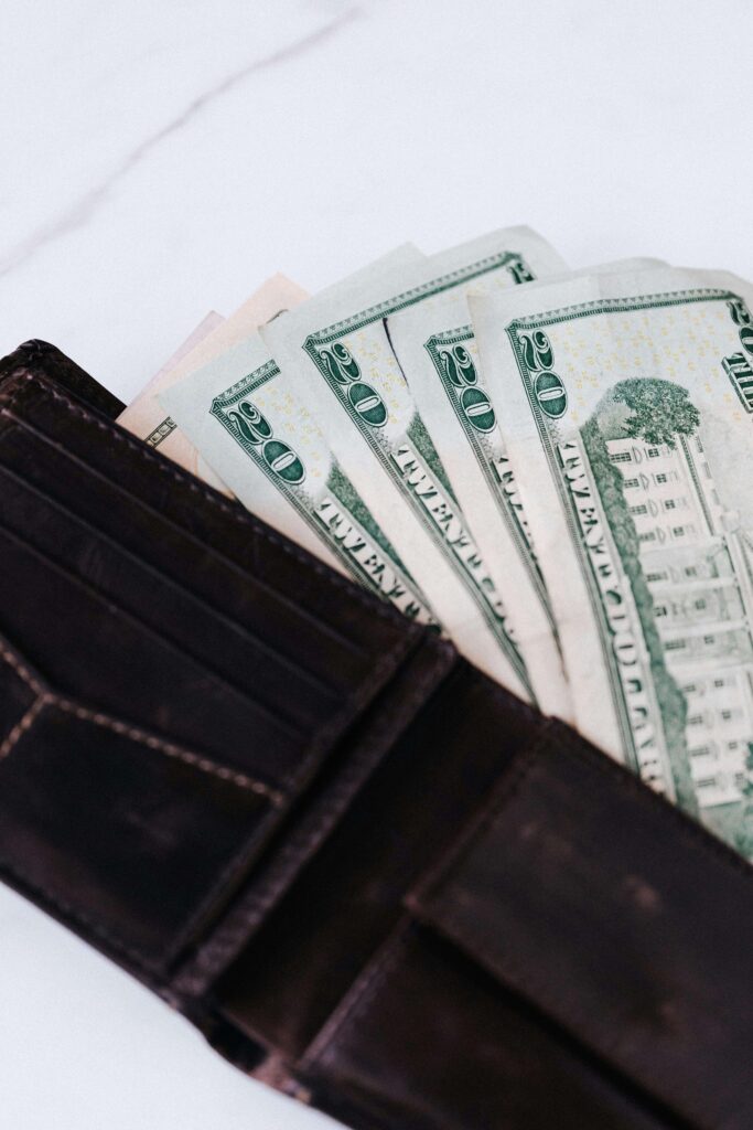 A wallet filled with twenty-dollar bills rests on a white background. Financial discussions are essential in managing marriage expectations. A premarital relationship therapist in Delray Beach, FL, helps couples align financial goals.