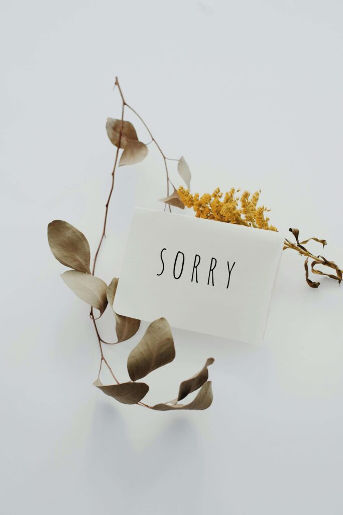 A white card with the word "sorry" beside dried leaves. Honest communication about relationship expectations supports strong marriages. Premarital relationship counseling in Delray Beach, FL, builds trust.