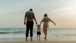 Parents hold their young child's hands on a beach. When your child triggers overwhelming anxiety, can you still be present? Anxiety therapy in Delray Beach, FL, helps parents manage their emotional responses while staying connected.