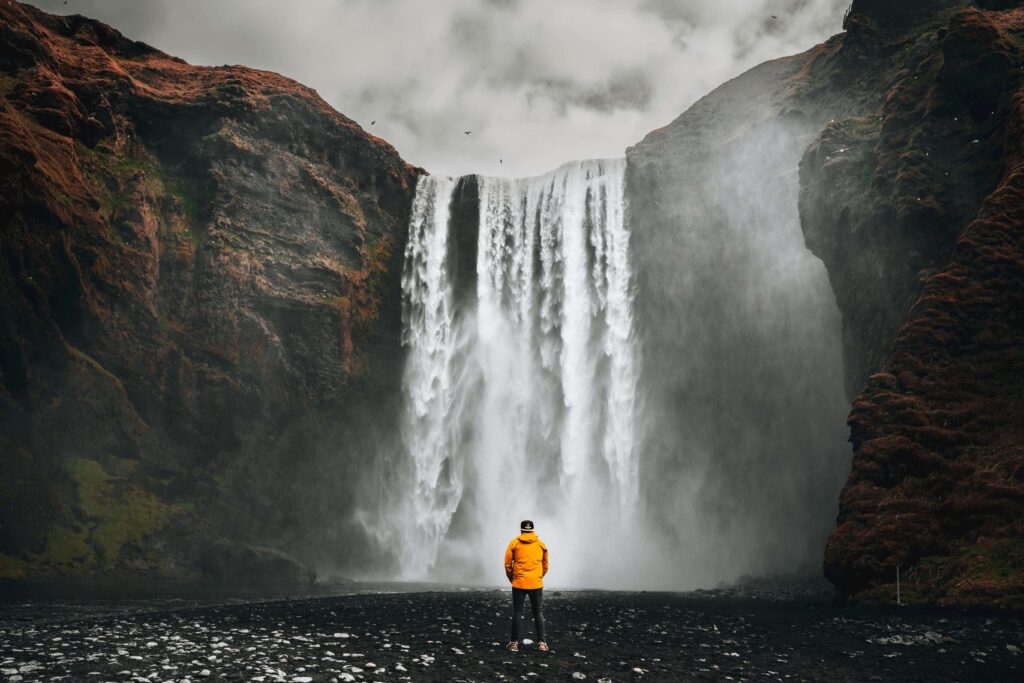 Person standing | online anxiety treatment in delray beach, fl | anxiety counselor | anxiety therapy davis | Delray Beach, Florida | Highland Beach | Palm Beach County | Boynton Beach | The Village by the Sea | Del-Ida Par A lone person stands facing a towering waterfall, surrounded by vast natural energy. Are you searching for natural anxiety solutions? An anxiety therapist in Delray Beach, FL, can help you regain balance and confidence step by step.