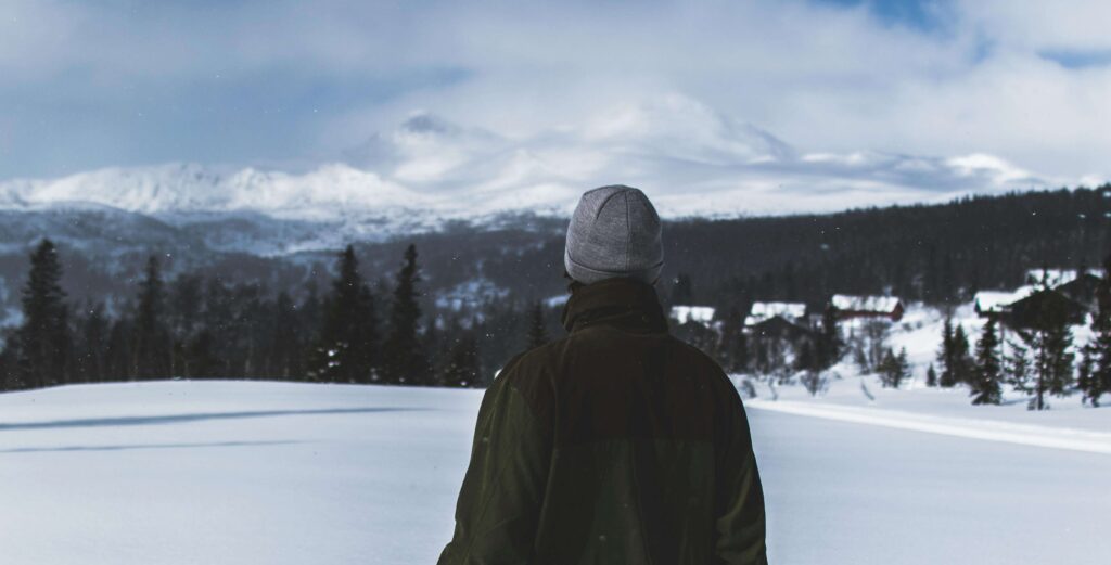 A man stands alone in a snowy landscape, gazing toward distant mountains and a quiet horizon. Unhealed trauma often fuels anxiety by keeping the nervous system on high alert. Anxiety therapy in Delray Beach, FL, supports healing by restoring emotional balance and resilience.