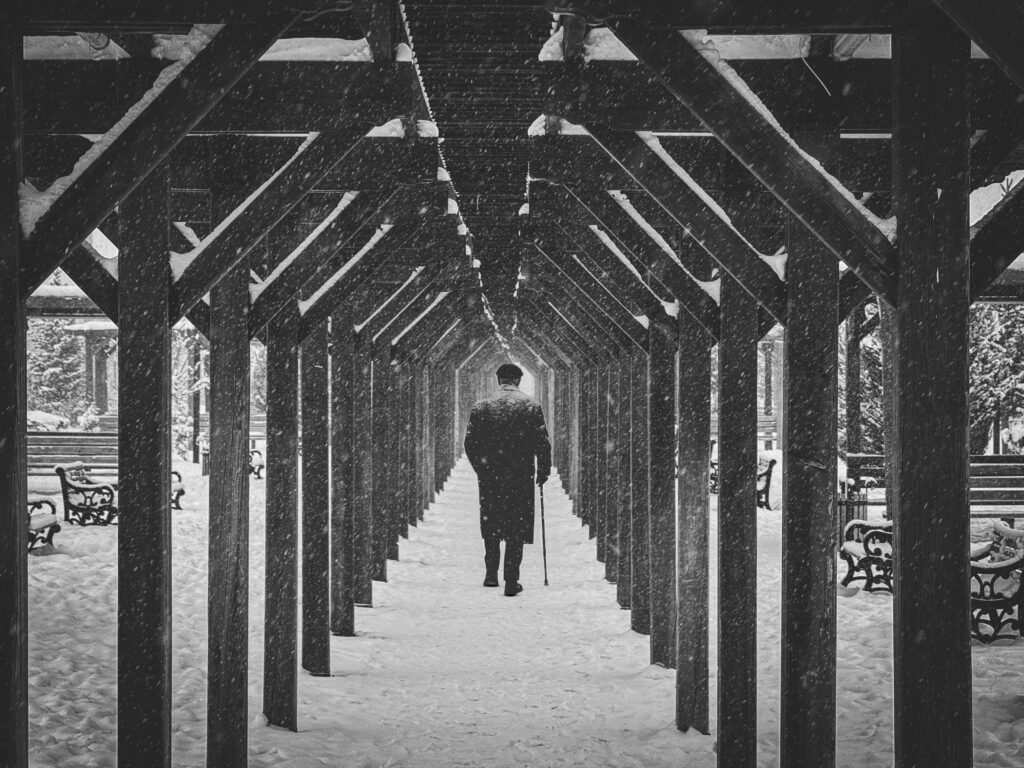 A solitary figure walks through a snow-covered corridor, framed by repeating wooden beams and falling snow. Trauma and anxiety can create a sense of isolation and emotional distance. An anxiety therapist in Delray Beach, FL, helps individuals reconnect, heal, and move forward with confidence.