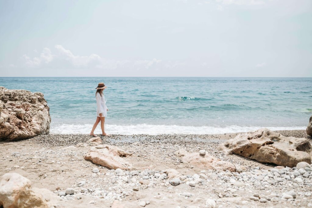 A woman walks alone on a rocky beach. When parenting anxiety feels overwhelming, do you need space or support? An anxiety therapist in Delray Beach, FL, can help you balance self-care with being an available, regulated parent.