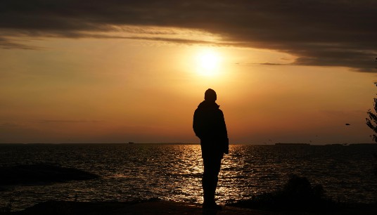 Silhouette of a man thinking while facing a dramatic sunset over a calm ocean. Overthinking can leave you feeling isolated and stuck inside your own mind. An anxiety therapist in Delray Beach, FL, can help you find peace and clarity.