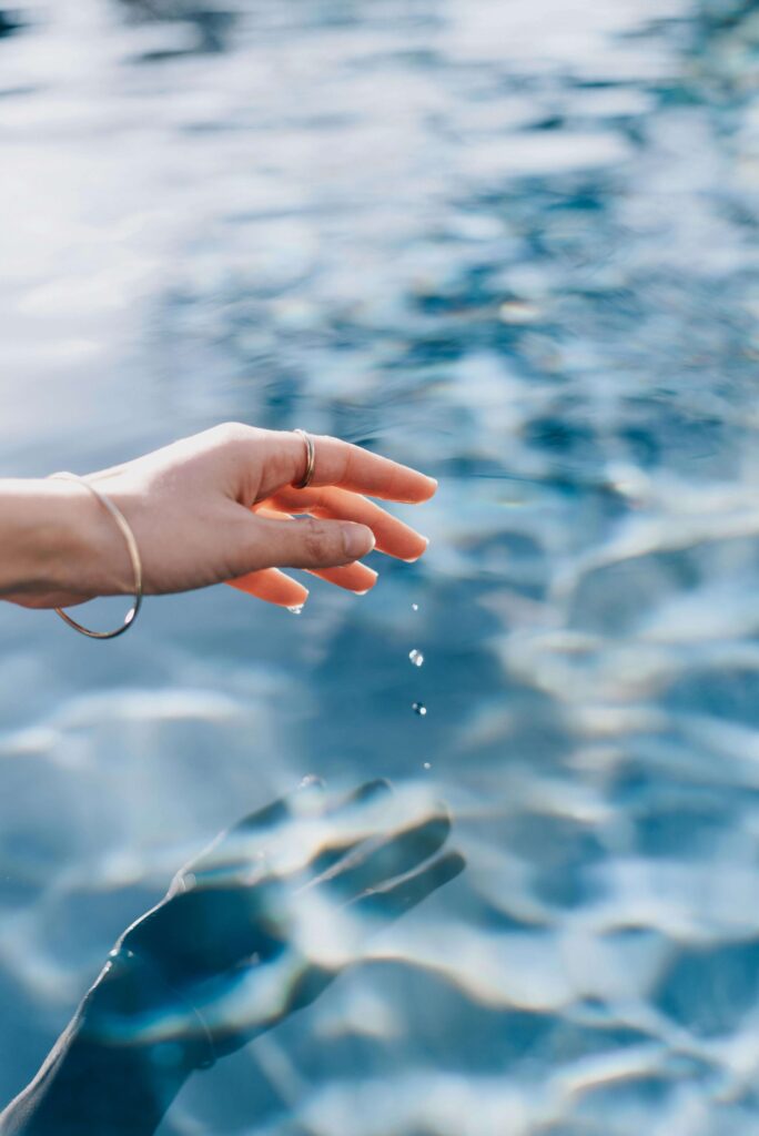 A woman's hand lets water droplets fall from her fingertips. Is eye contact something that drains rather than connects you? Anxiety therapy in Delray Beach, FL, offers compassionate support to help you understand and navigate these challenges. 