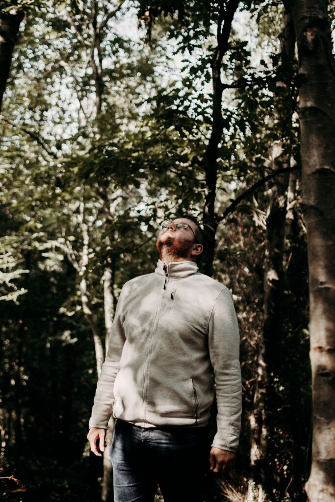 A man stands in a wooded area, head tilted back and eyes closed as he faces the trees. Could anxiety show up out of nowhere, even when nothing seems wrong? An anxiety therapist in Delray Beach, FL can help you uncover the root causes behind it.